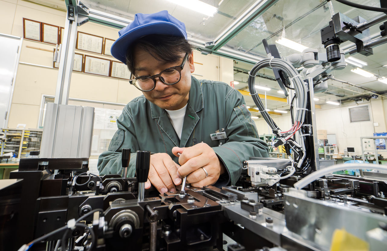 男性社員が精密な生産設備を調整している様子