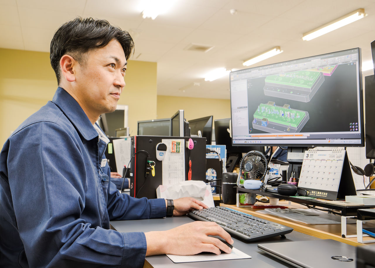 男性社員がデュアルモニターで3D CADソフトを使用し、設備の設計を行っている様子