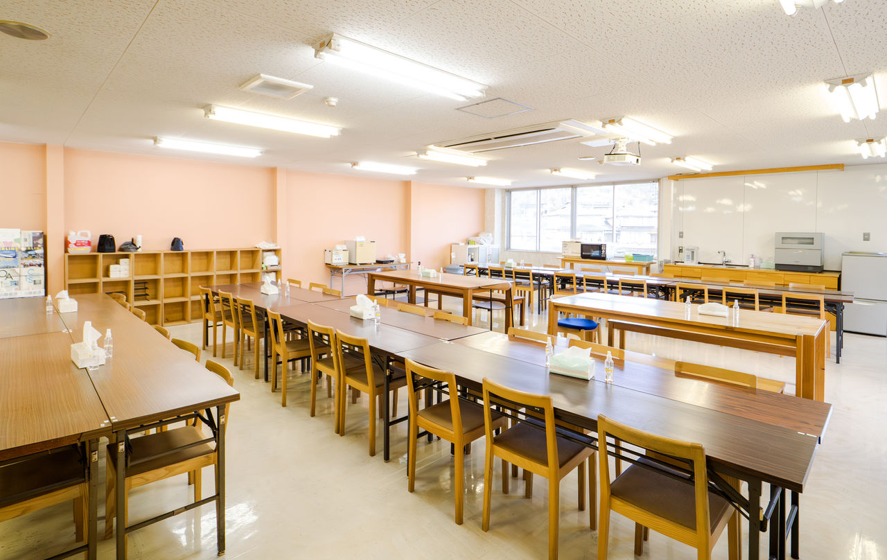 多数の木製テーブルと椅子が整然と並べられた、広々とした明るい社員食堂