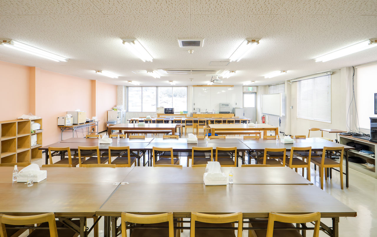 多数の木製テーブルと椅子が整然と並べられた、広々とした明るい社員食堂