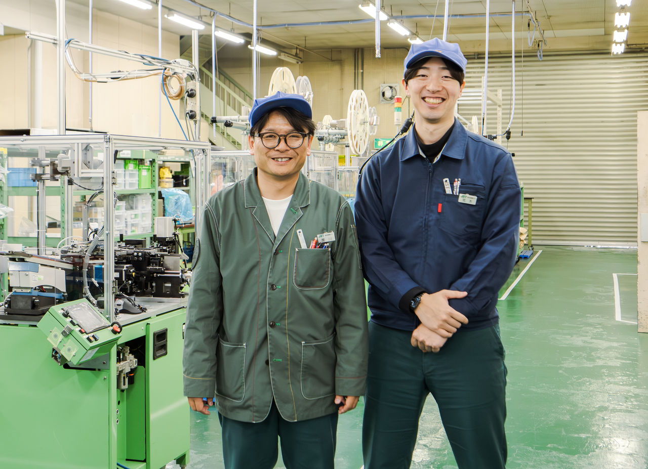 2名の男性社員がそれぞれデザインの異なるユニフォームを着用している様子。