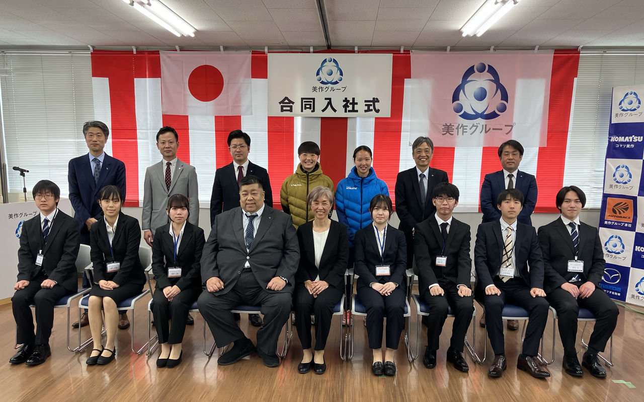 美作グループ合同入社式での、新入社員7名と大部由美さんおよび関係者の集合写真。