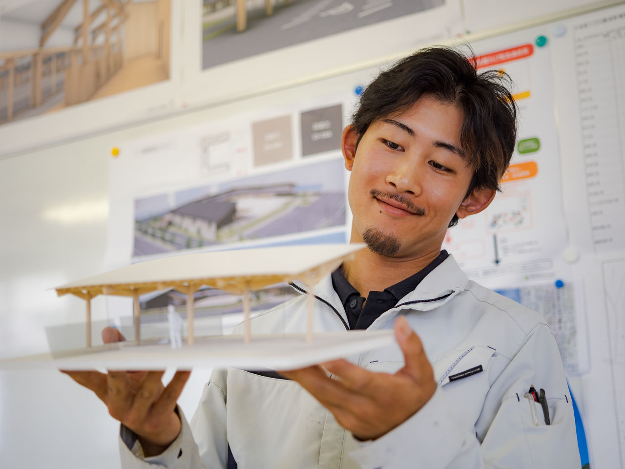 完成予想の建築模型を両手で持ち笑顔で見つめるTさん