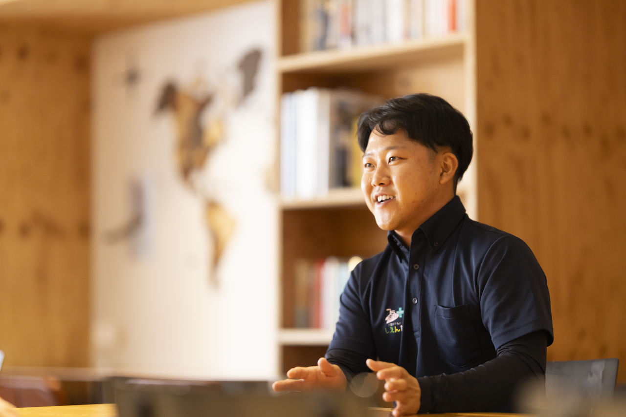 笑顔で両手を広げながら語る寺坂実成さん