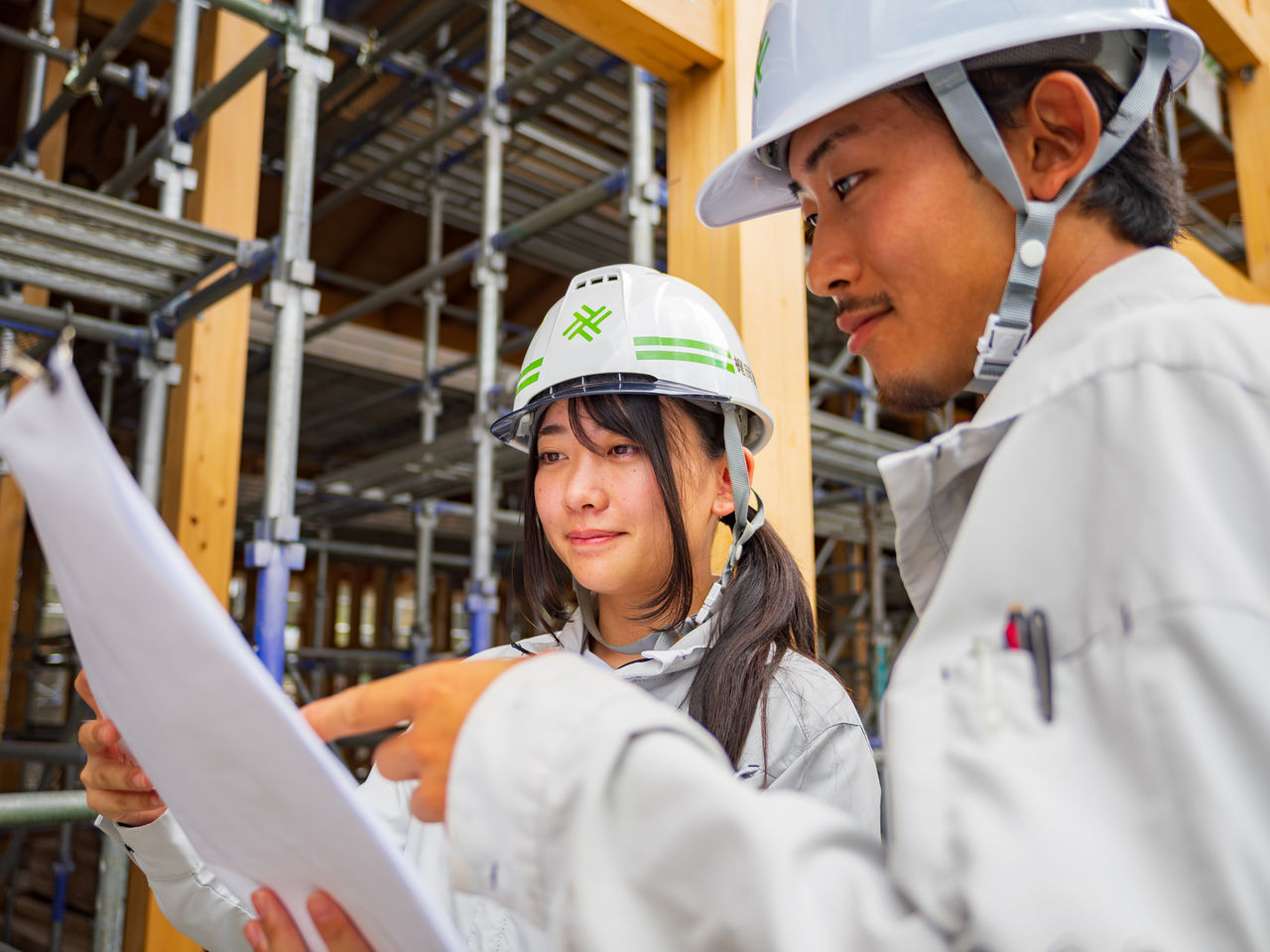 建築現場で広げた図面を指し示す2名の作業員