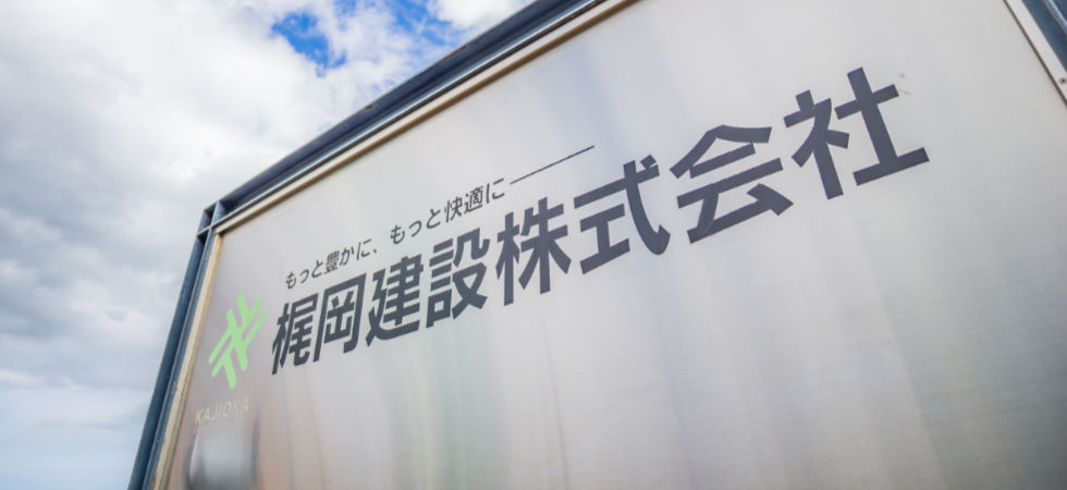 「もっと豊かに、もっと快適に――梶岡建設株式会社」と書かれた看板
