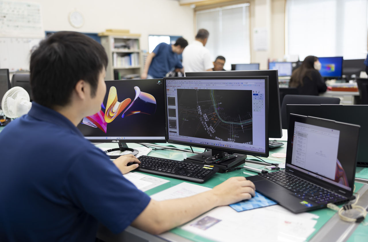 オフィスでパソコンのモニターにCAD図面を表示し作業を進める社員