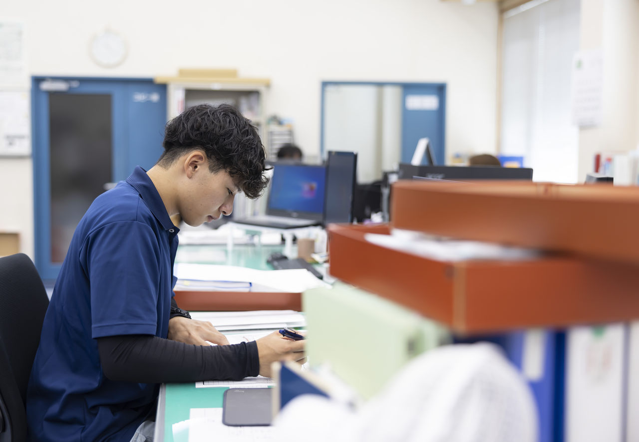 オフィスのデスクでペンを手に真剣な表情で書類に向き合う社員
