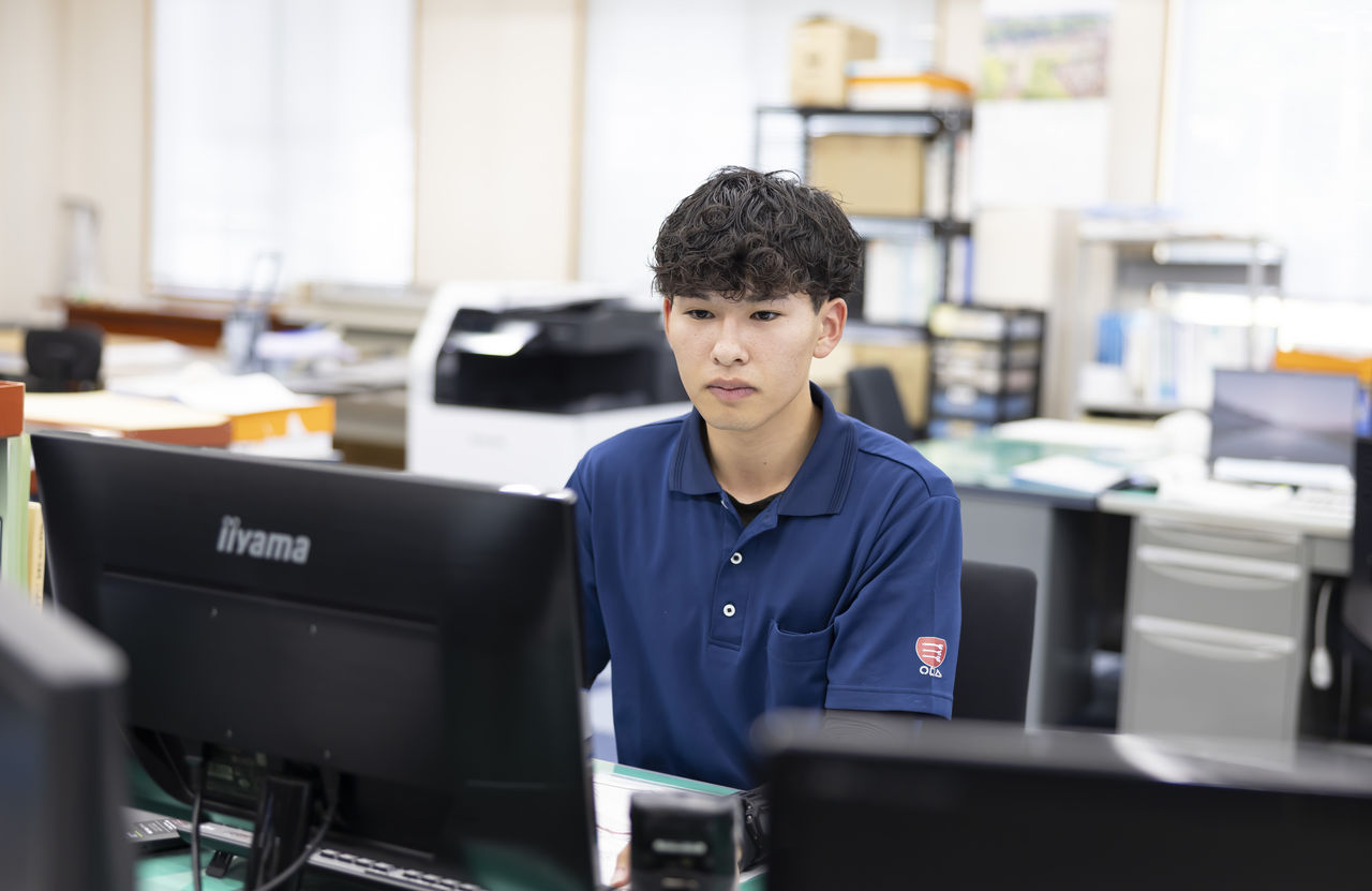 オフィスでパソコンに向かい真剣な表情で画面を見つめる貝阿弥明希さん