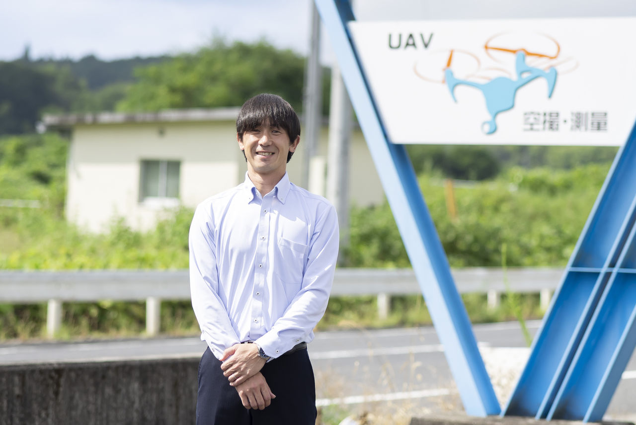 オーエスエーの看板の前に立ち穏やかな表情を浮かべる代表取締役の杉本光彦さん