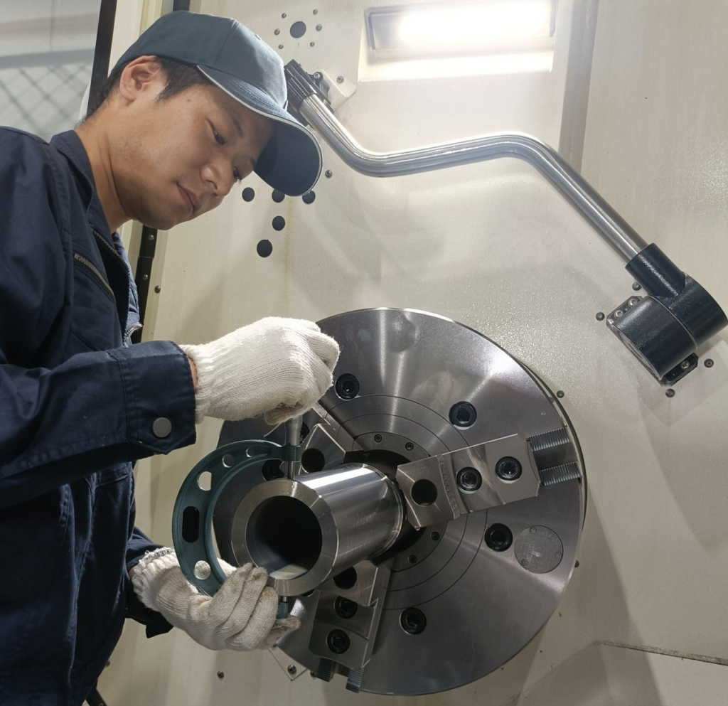 機械の前で金属部品の加工作業を行っている様子