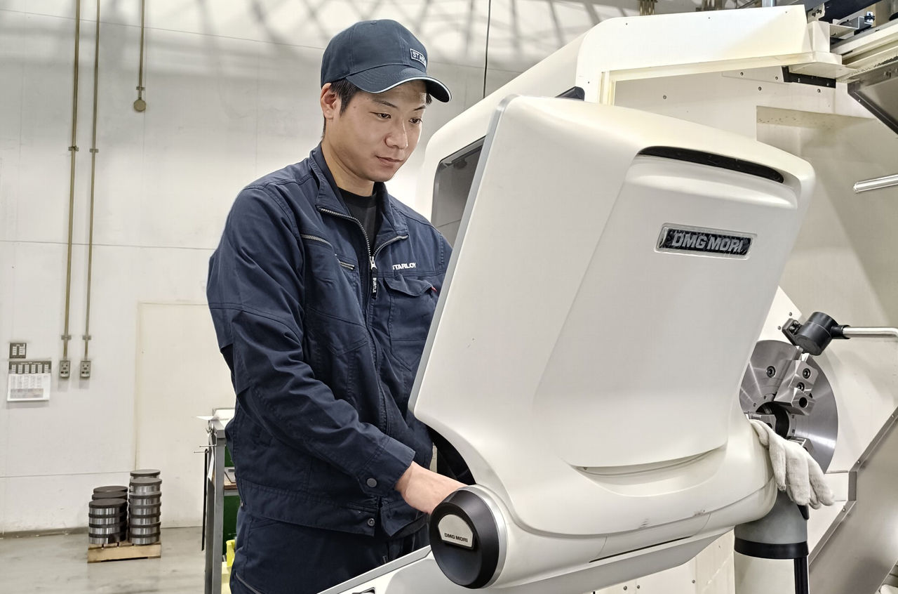 大きな機械の操作パネルを見ながら作業を進めている様子