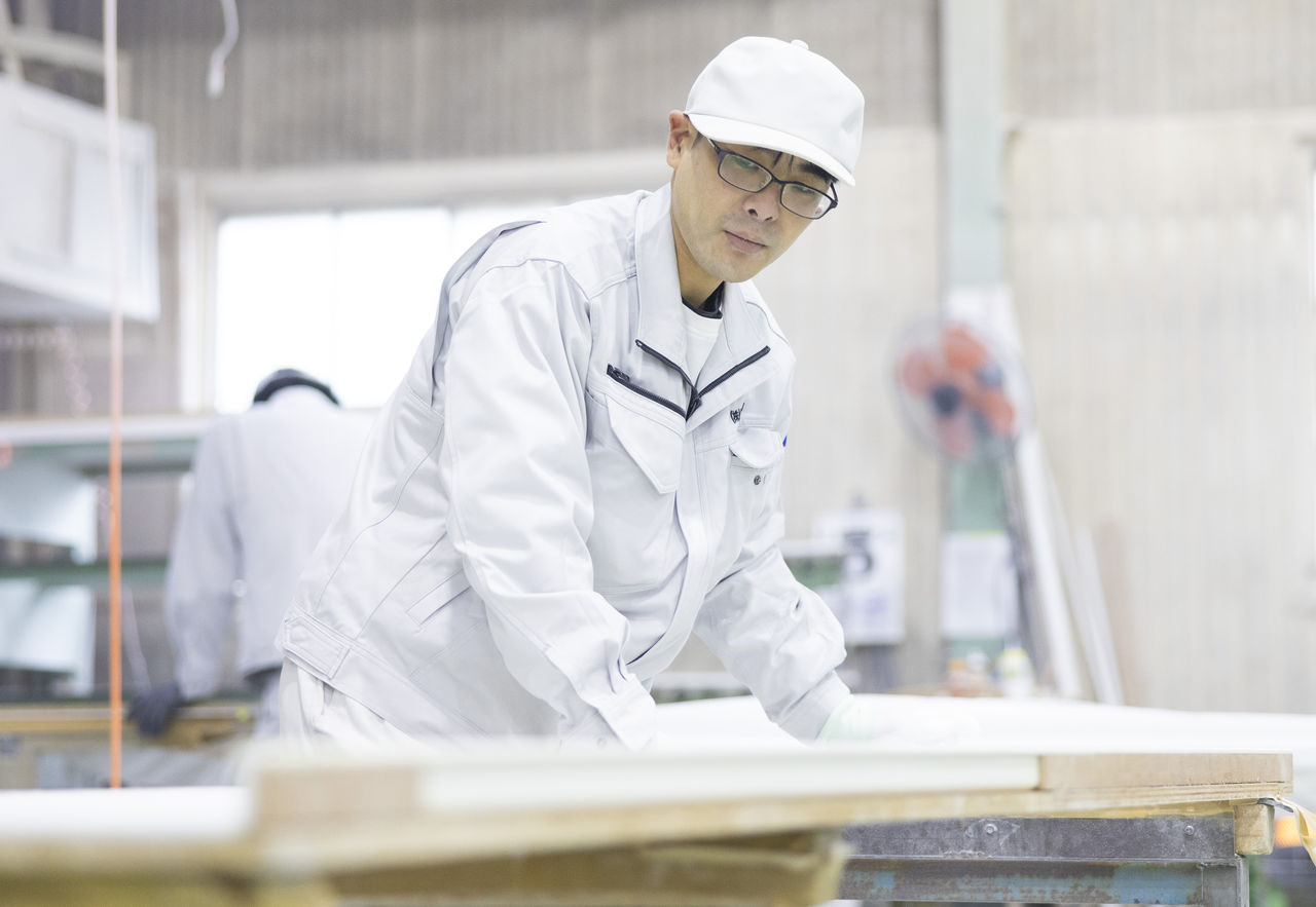 白い作業着と帽子姿で、カウンターの加工作業を行っている様子