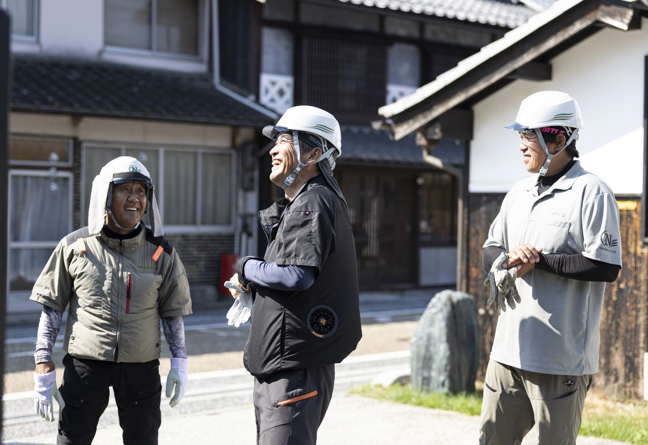 屋外で仲間たちと笑顔で歓談する作業員たち