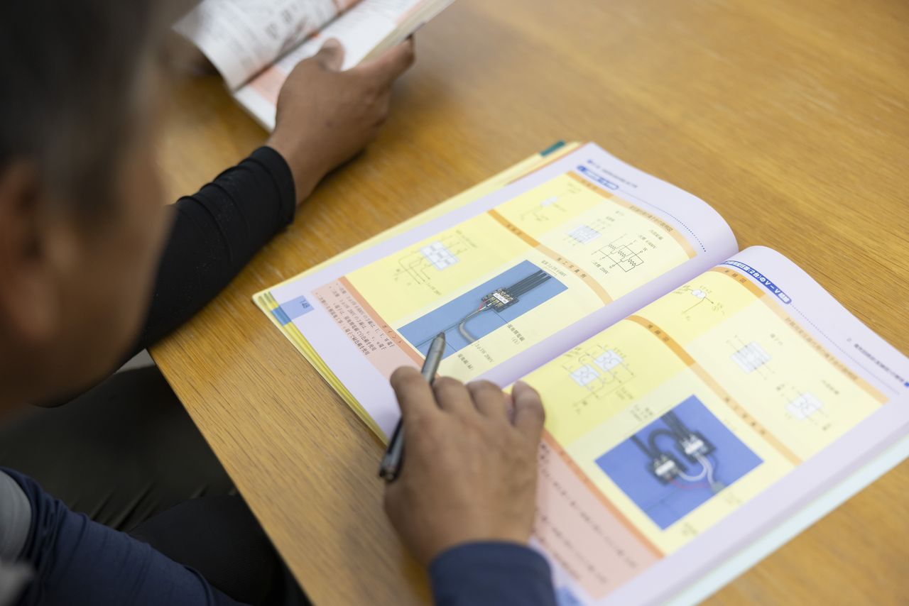 電気工事のテキストを開いて勉強する日並昌平さんの手元
