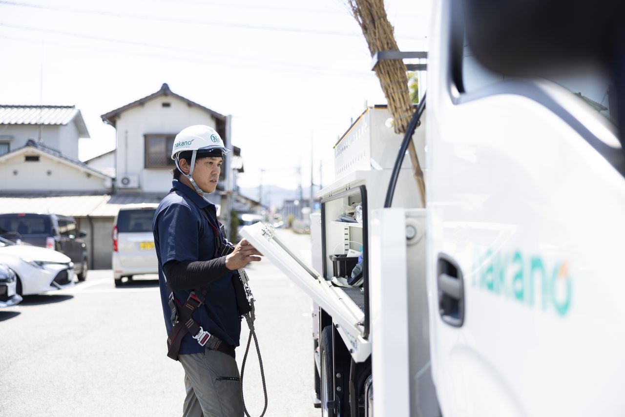 作業車の側面収納ボックスを開けて道具を取り出す西田優也さん