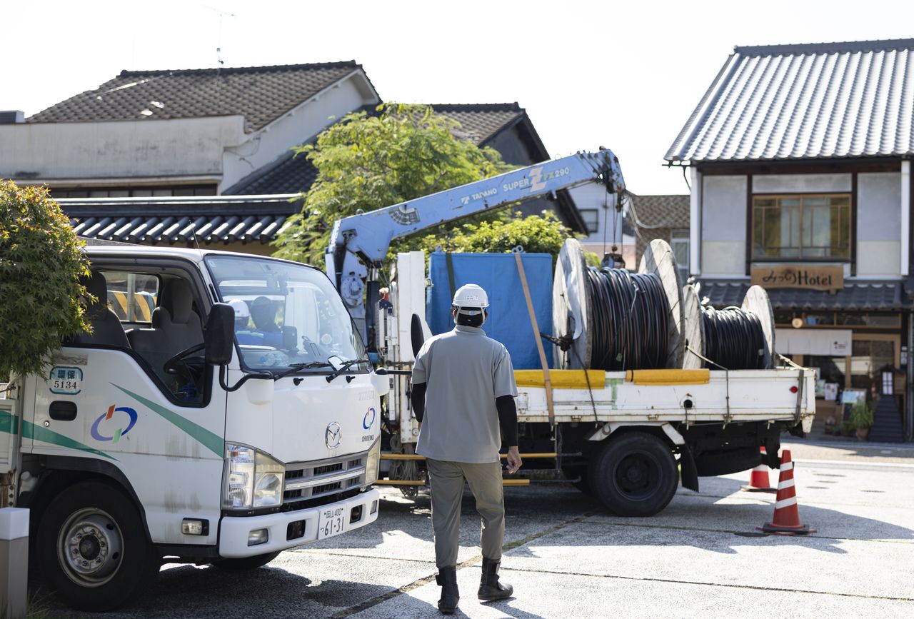 電線ドラムを積んだトラックへ向かって歩く西田優也さんの後ろ姿