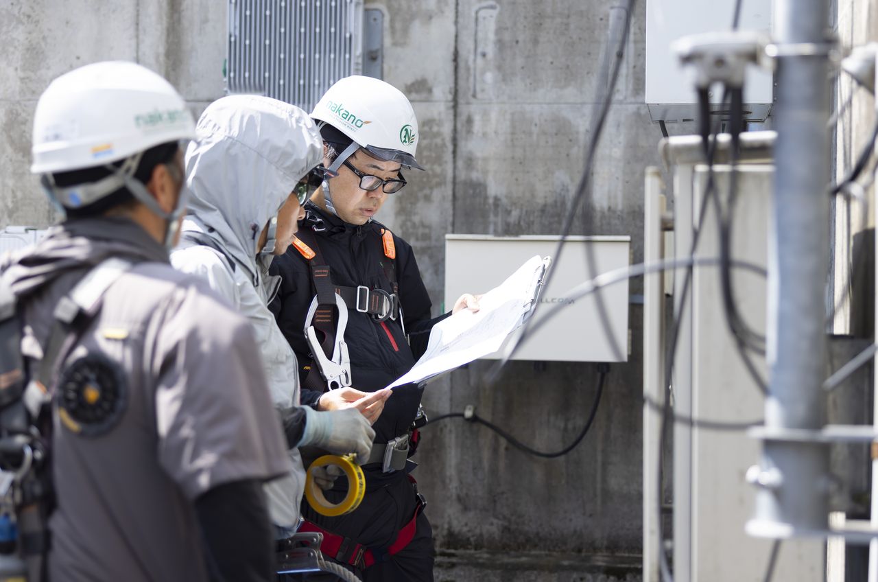 図面を見ながら作業手順を確認し合う3人のスタッフ