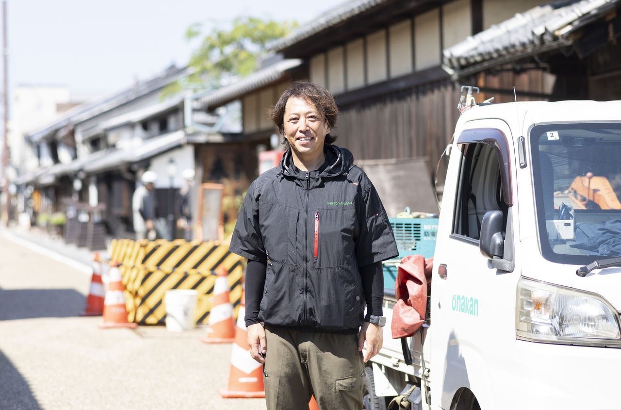 城東地区の町並みで作業トラックの前に立つ中野裕太さん