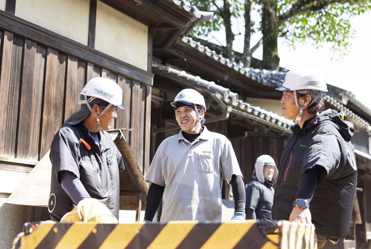 現場の安全柵の横で中野裕太さんと笑顔で談笑するスタッフたち