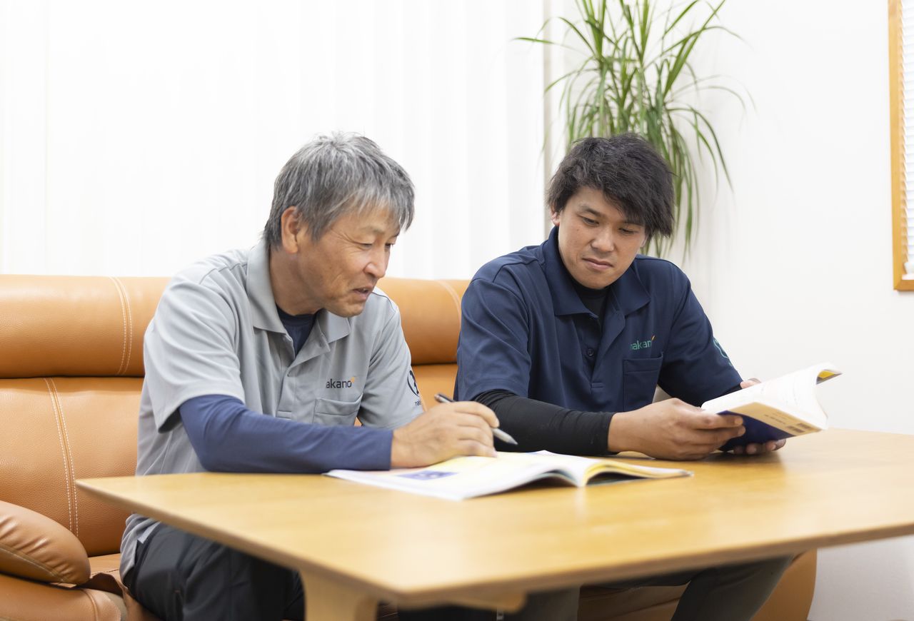 ソファー席で参考書を広げて資格取得の勉強をする2人のスタッフ