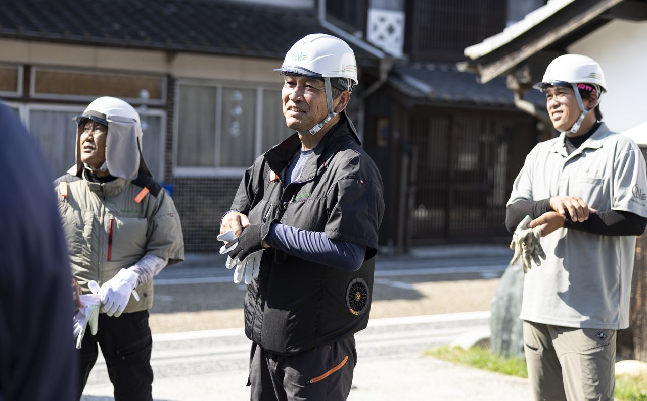屋外で仲間たちと笑顔で談笑する山本智弘さん