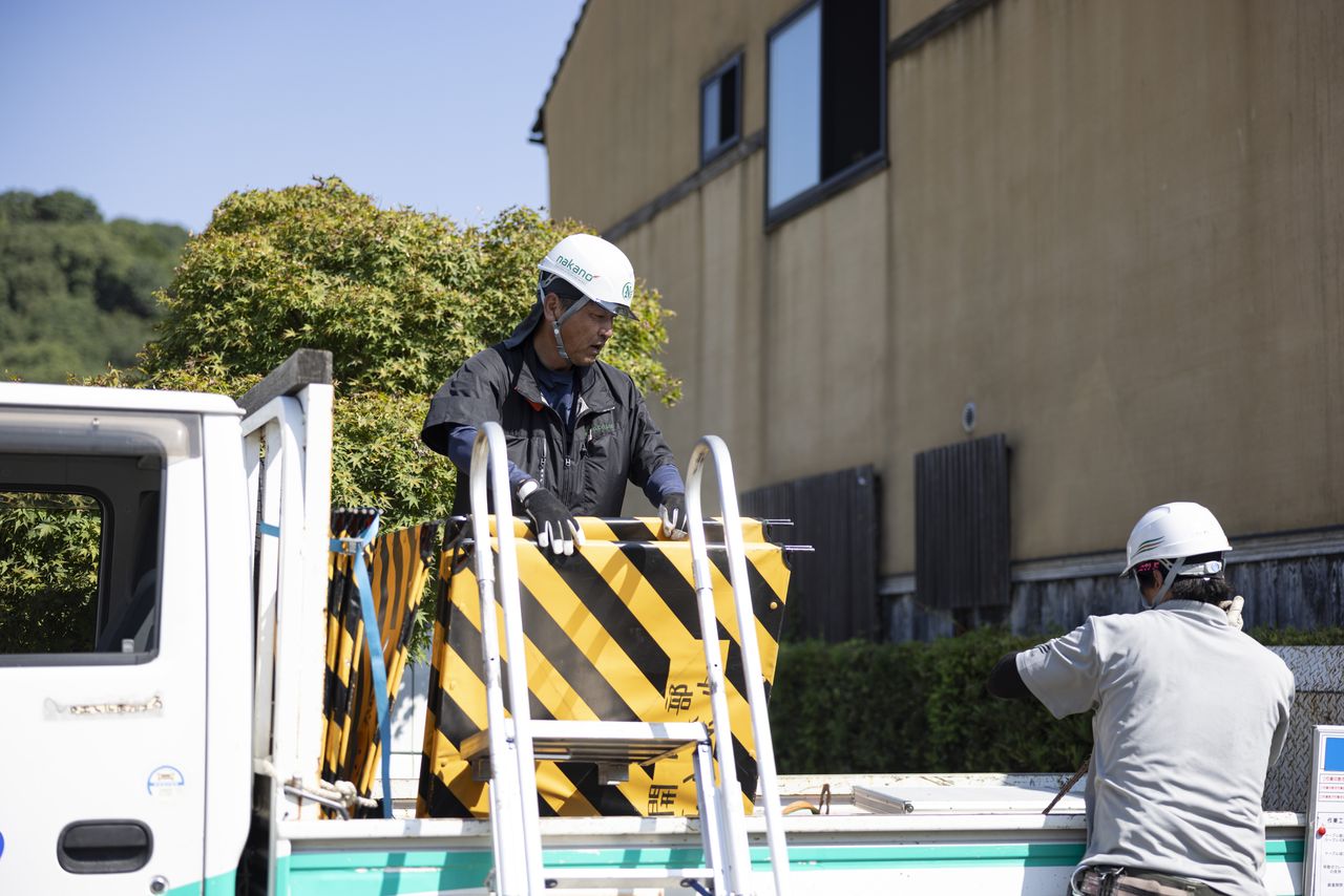 軽トラックの荷台で安全柵を積み下ろし片付けを行う作業員たち