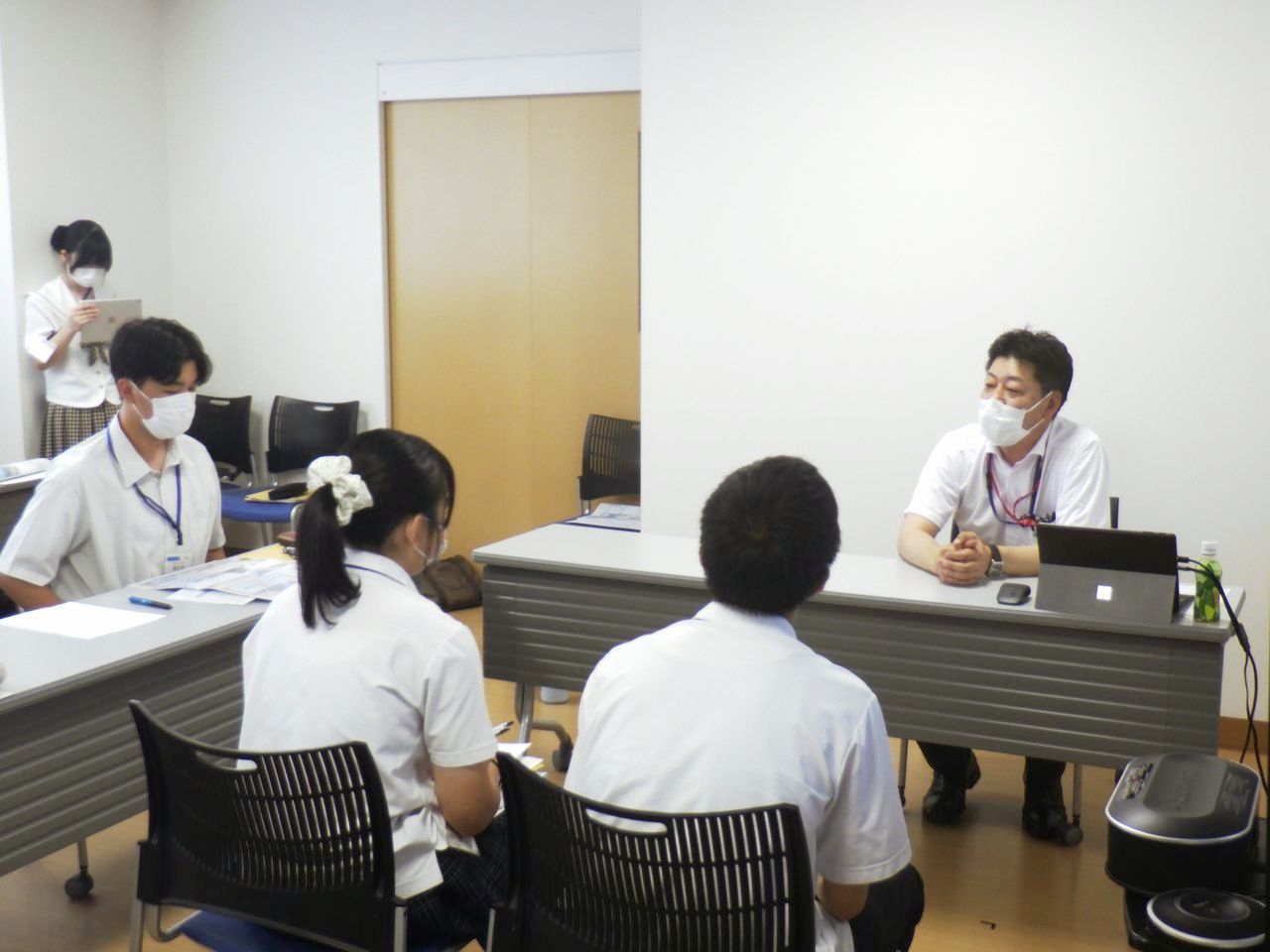 石川病院の会議室で佐藤政孝事務局長を囲み取材を行う高校生たち