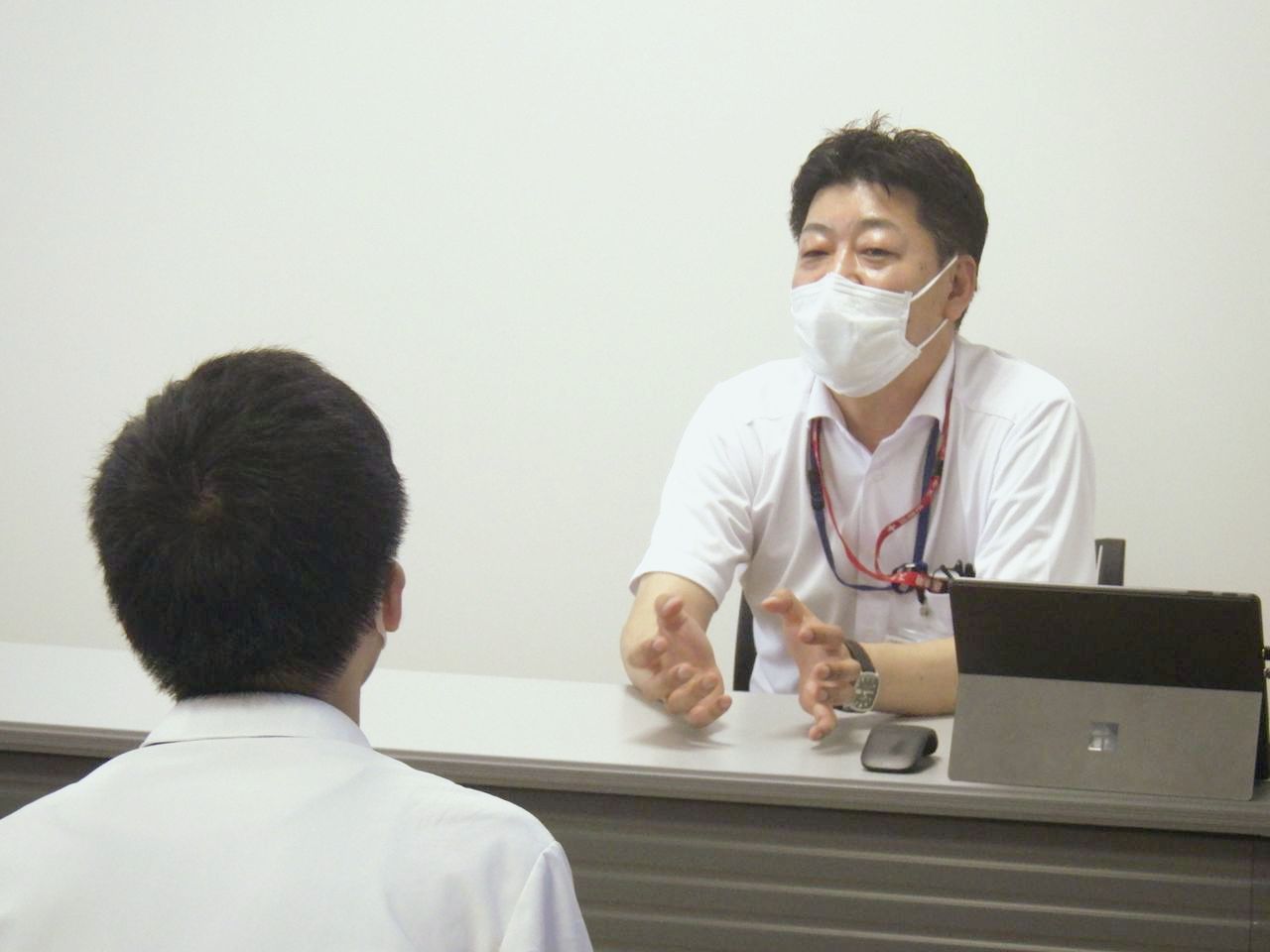マスクを着けて両手を広げて話す佐藤政孝さん