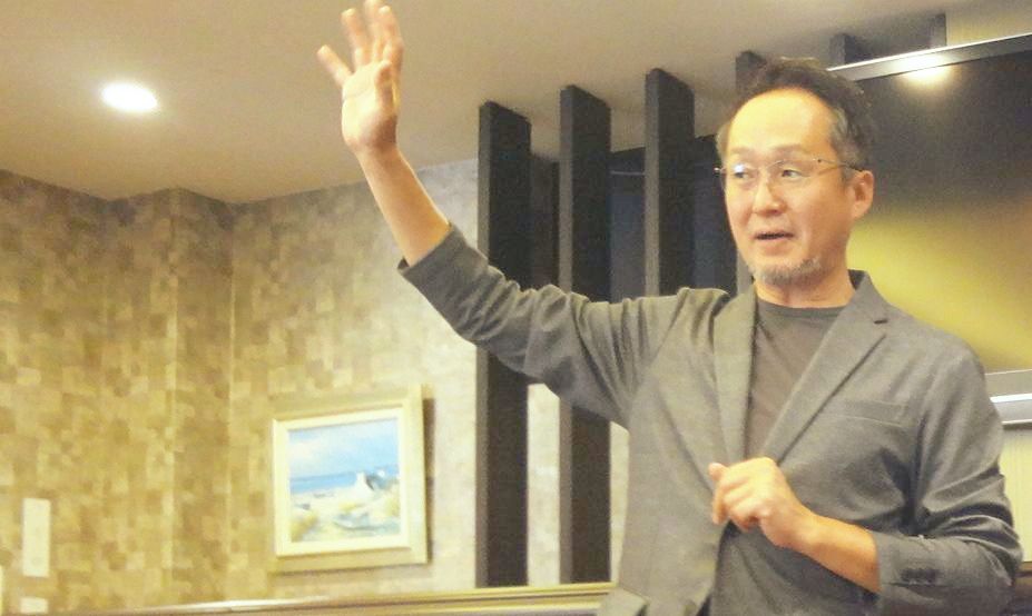 会議室で両手を胸の前に出して話す菅田拓平さん