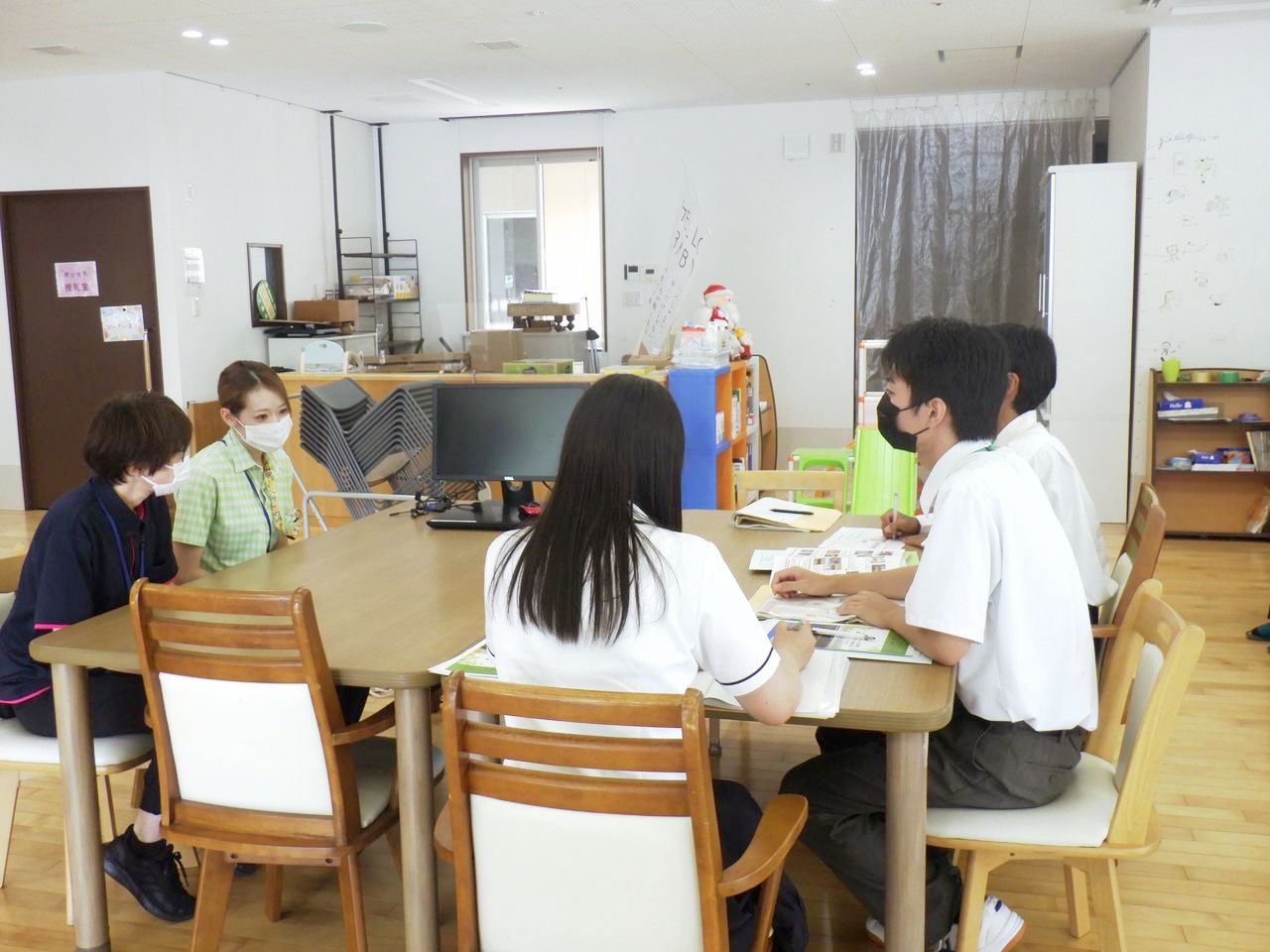 施設内のテーブルを囲んで職員と対面で座る高校生たち