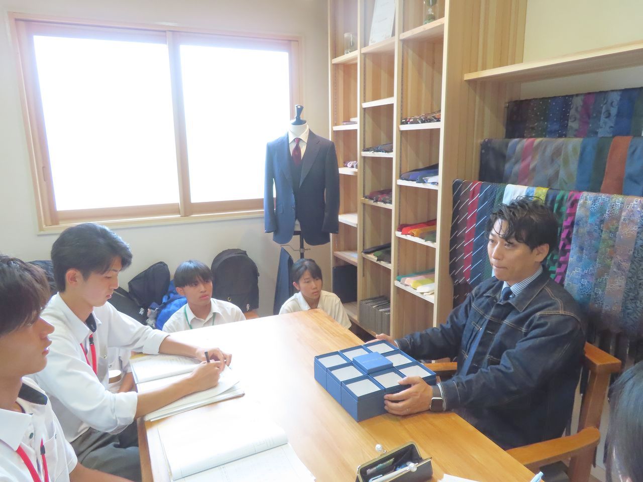 黒いギフトボックスを手にして高校生たちに話す笏本達弘さん