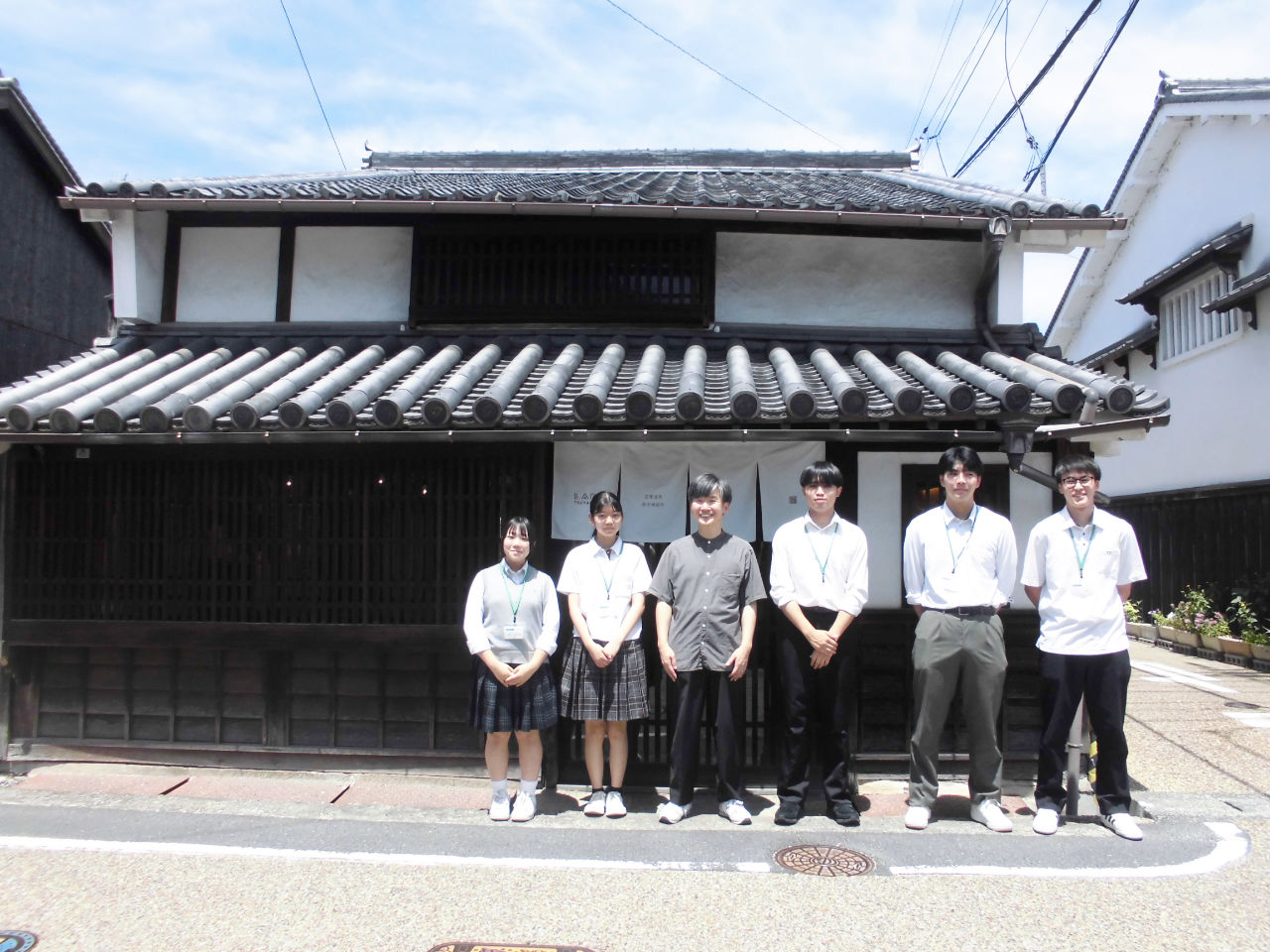 和田デザイン事務所の建物の前で並ぶ和田優輝さんと高校生たち